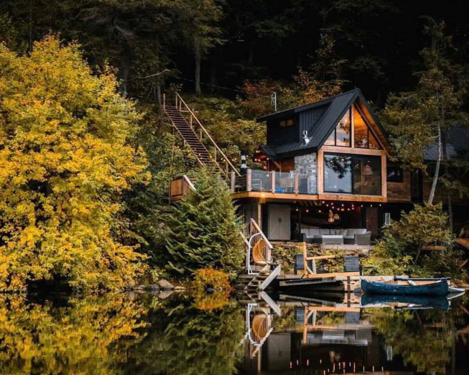 A lake house at dusk with a canoe at the dock